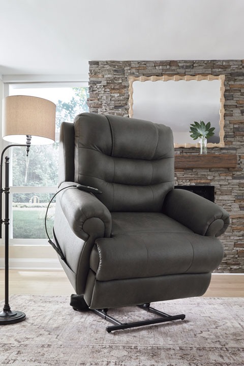 Gray leather recliner chair in a bright living room with a stone fireplace and mirror above the mantle